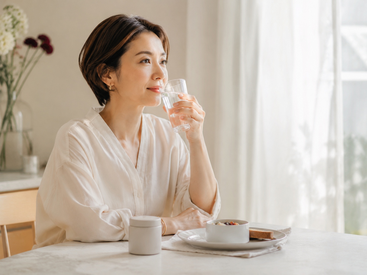 朝の食卓で水を飲む女性